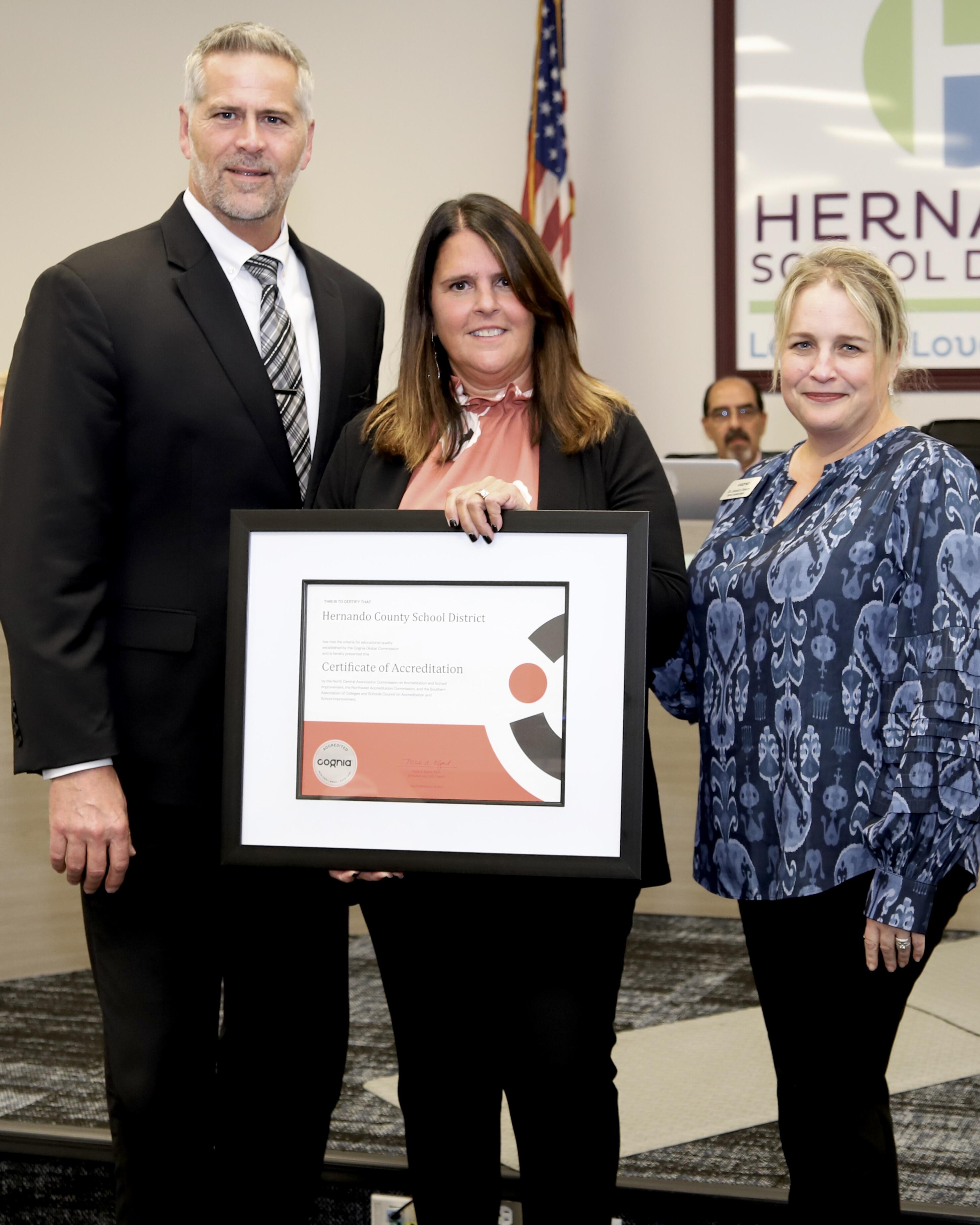 Dr. Jessica Swere presents accreditation certificate to Superintendent and Assistant Superintendent